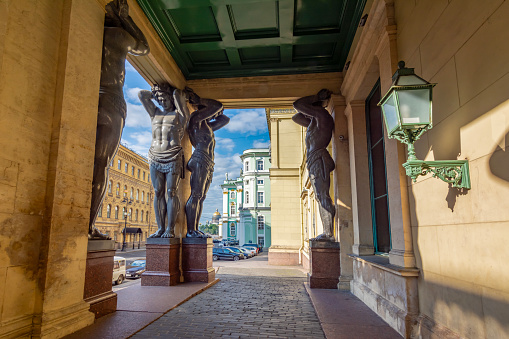 Saint Petersburg, Russia - August 2019: Portico of New Hermitage building with Atlantes and St. Isaac's Cathedral at background in Saint Petersburg