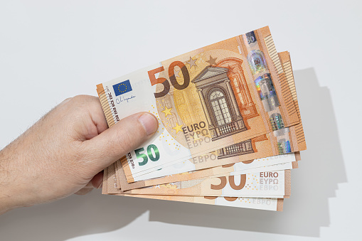 Hand holding many fifty euro banknotes on white background