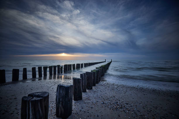 Breakwaters on beach, Netherlands, Zeeland, Domburg. The sun is setting and the is a storm coming