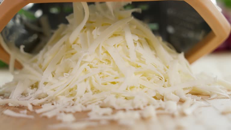 The cheese is grated on a coarse grater. Close-up, macro, front view