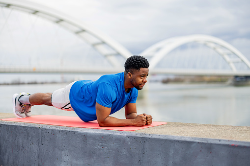 The pulse of progress beats strong as a young African American man exercises outdoors, his dedication illuminating the potential of open spaces as venues for health, wellness, and community inspiration