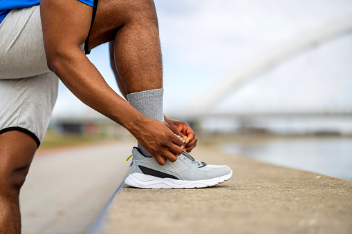As he ties his shoes outdoors, he grounds himself in determination and focus, each lace a reminder of the importance of a strong foundation in achieving fitness goals and pushing beyond limits
