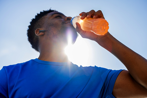 An African American man pauses to fuel his workout with an energy drink, each sip recharging his determination and endurance. This moment captures the synergy between nutrition and exercise, emphasizing the role of hydration in achieving fitness goals