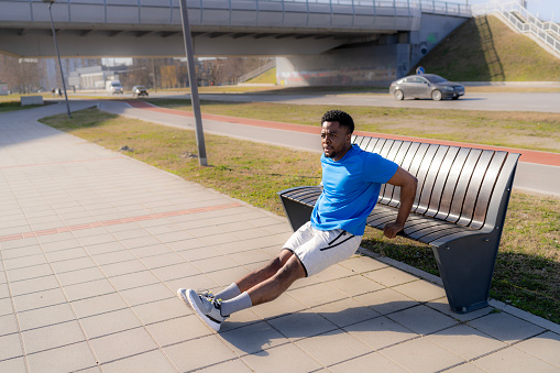 A young African American man practices the art of urban exercise, his outdoor routines a creative response to the challenge of staying fit in the fast-paced urban environment