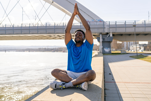 With each breath taken during his outdoor relaxation exercises, a young African American man breathes life into his practice of calm, showcasing how the simplicity of breath work can transform the outdoor space into a sanctuary of peace