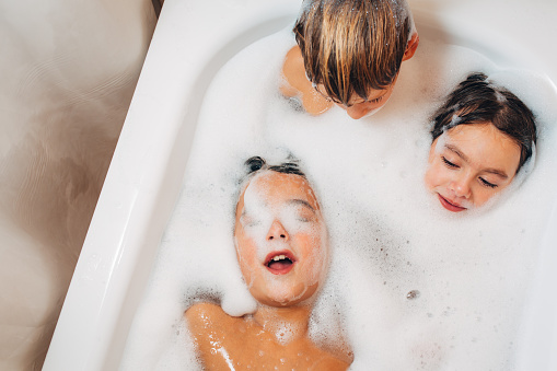 High angle view shot of children lying in a bathtub and having fun washing with water and soap