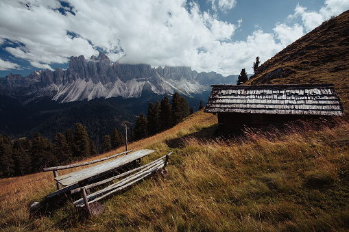 small wooden hut in front of a lake with mountains in the background