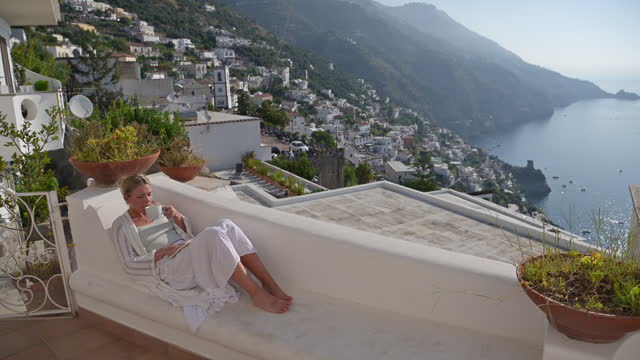 Woman reading a book on a villa balcony or terrace in Praiano Italy.