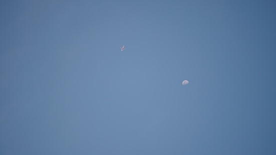 Airplane to the sky with moon during daytime.