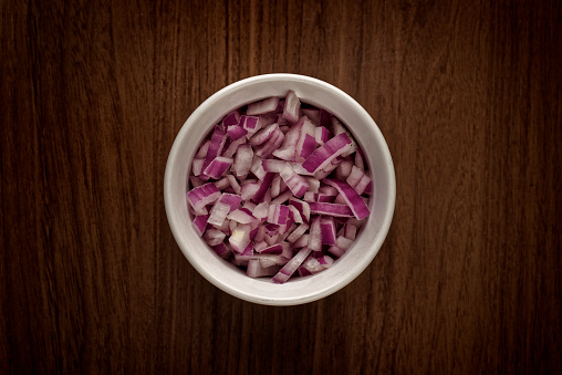 A top view of a diced onion in a bowl on a table