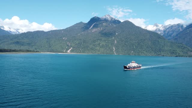 Car ferry on the fjords of Patagonia with green forest mountains in background
