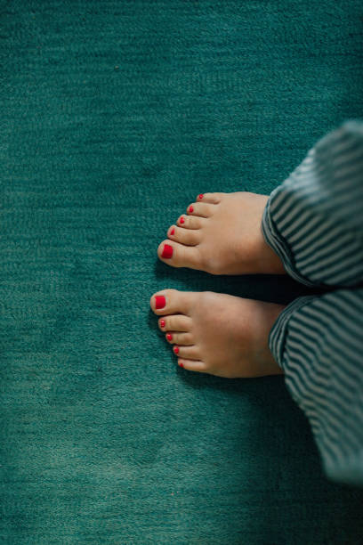 istock feet with red pedicure on teal carpet 2048962100