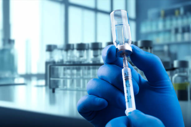 istock Doctor's hand with syringe and vaccine on laboratory background 2048962644