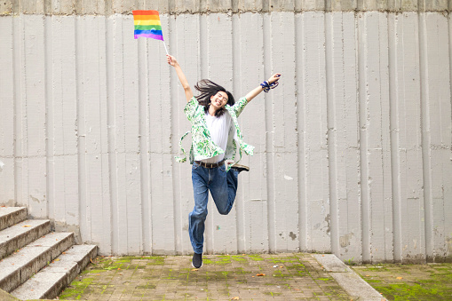 Joyful Man Jumps with Rainbow Gay Pride Flag: Celebrating LGBTQ+ Identity and Freedom with Energetic Spirit