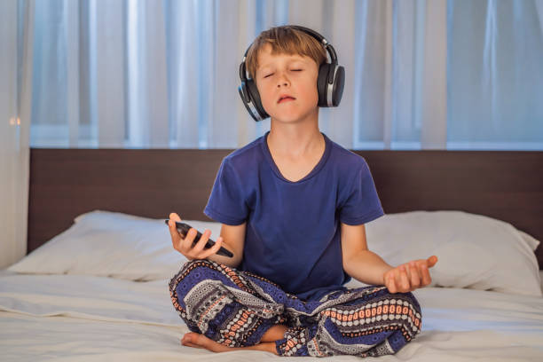 istock Boy meditates on bed using meditation app. sport, technology and healthy lifestyle concept 2049020749