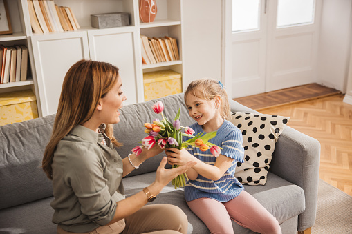 Happy daughter  giving bouquet of tulips to her mother for mother's day.