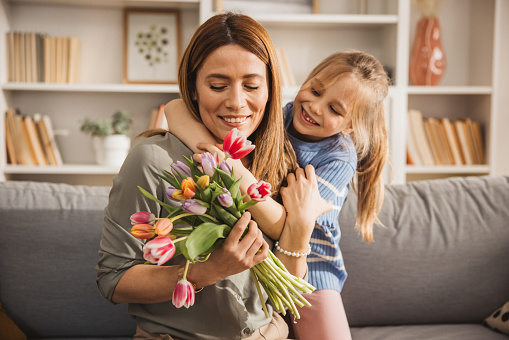 Happy daughter  giving bouquet of tulips to her mother for mother's day.