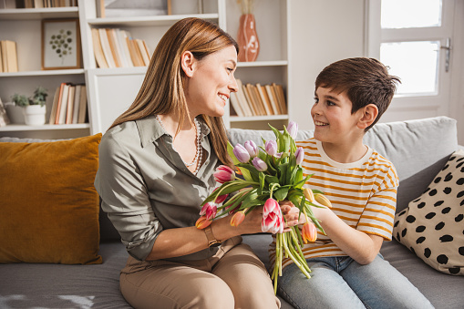 Happy son giving bouquet of tulips to his mother for mother's day.