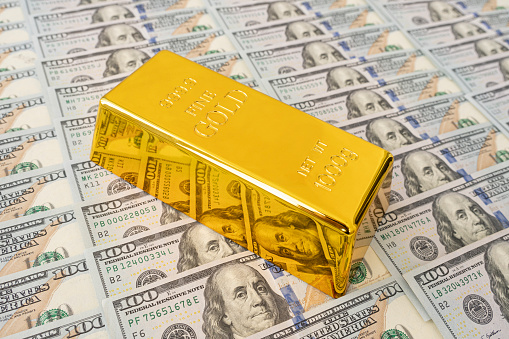 Gold bar on US dollar bill banknotes background. Concept of gold future trading, asset commodity trading or buy gold bars for investment.