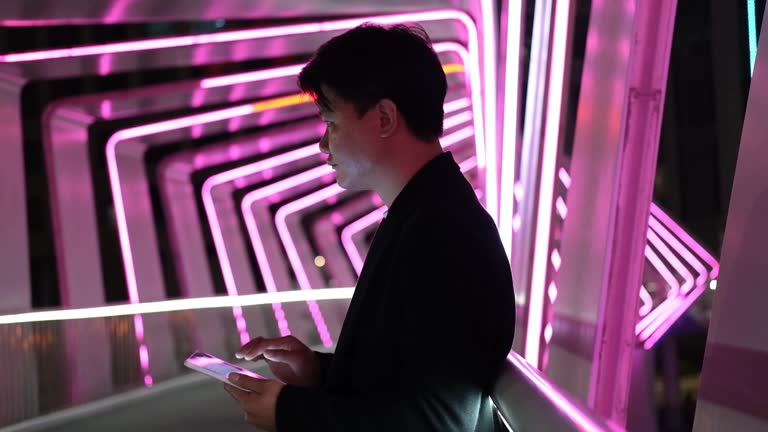 Asian man using tablet in glowing aisle