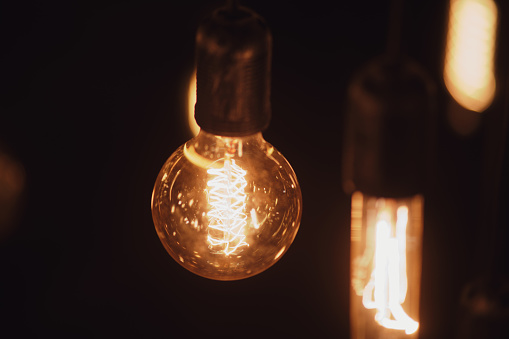 Vintage incandescent Edison light bulb glowing in the dark.