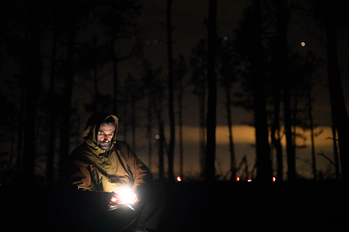 Mature man alone with his thoughts in the woods at night.