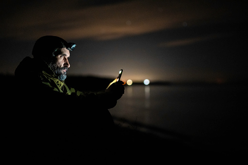 Mature man using phone at night in nature. Night life.