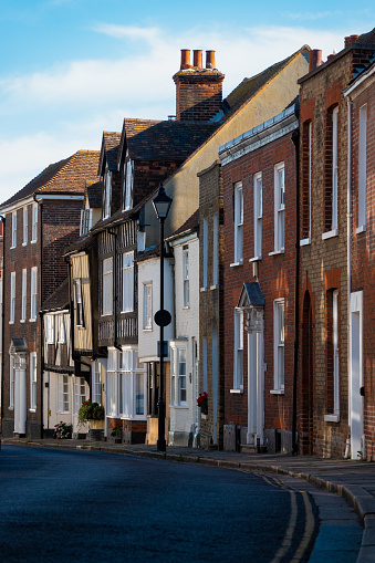 Quiet English street with charming townhouses in variety of architectural styles, from timbered facades to classic brickwork. Picturesque street with quaint terraced houses in old town of Sandwich.