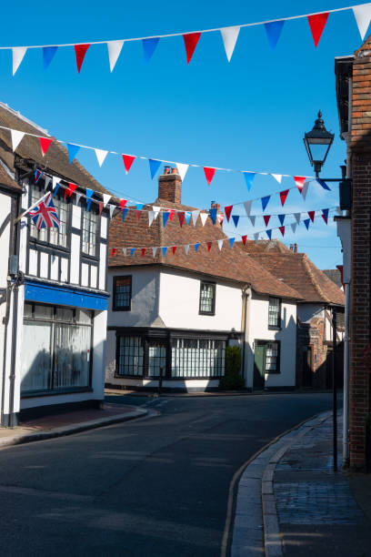 Festive spirit in a decorated street in the middle of a charming English town Festive spirit in a decorated street in the middle of a charming English town. Red, white, and blue bunting flags hang between medieval timbered townhouses in a picturesque historic town of Sandwich. sandwich kent stock pictures, royalty-free photos & images