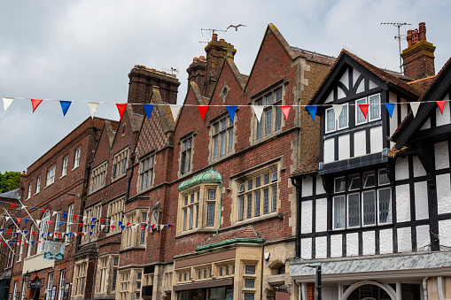 Cloudy skies over classic Tudor architecture and festive bunting in historic English town. Historic charm of stunning medieval houses and festive spirit while walking through picturesque Arundel.