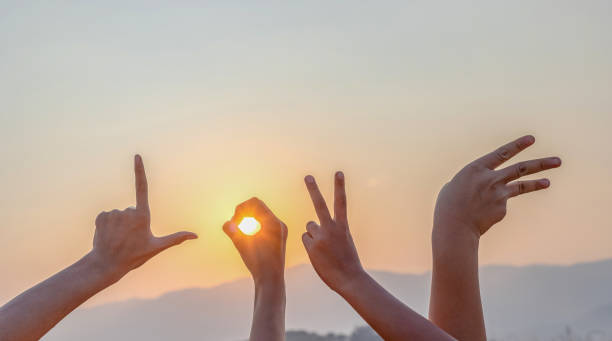 las manos muestran la letra l, o, v, e en el fondo de la puesta del sol en lenguaje de señas - letter l human hand human finger human thumb fotografías e imágenes de stock