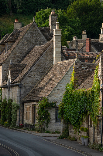Idyllic terraced houses with stone facades in charming village of Castle Combe. Picturesque little towns scattered along a range of rolling hills in famous tourist destination of the Cotswolds region.