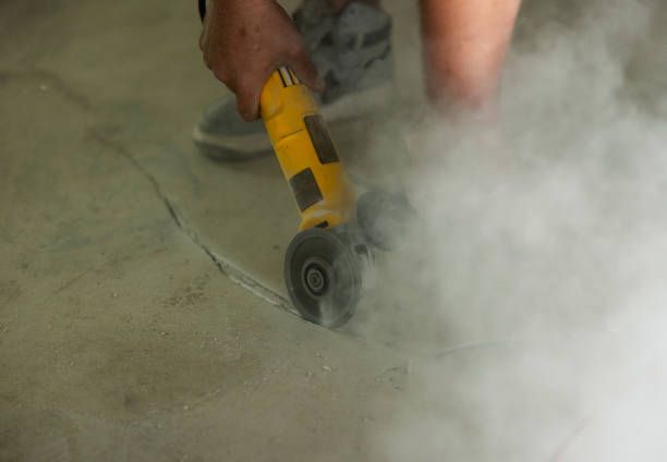 man working in rubber boots with a power cutter on the street