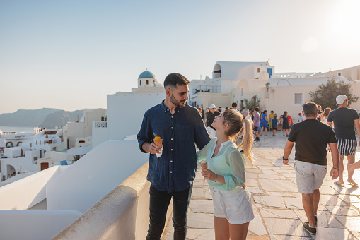 Oia, Santorini, Greece - July 3, 2021: Whitewashed buildings and the ruins of Castle of Agios Nikolaos on the edge of the caldera cliff, Oia village, Santorini, Greece