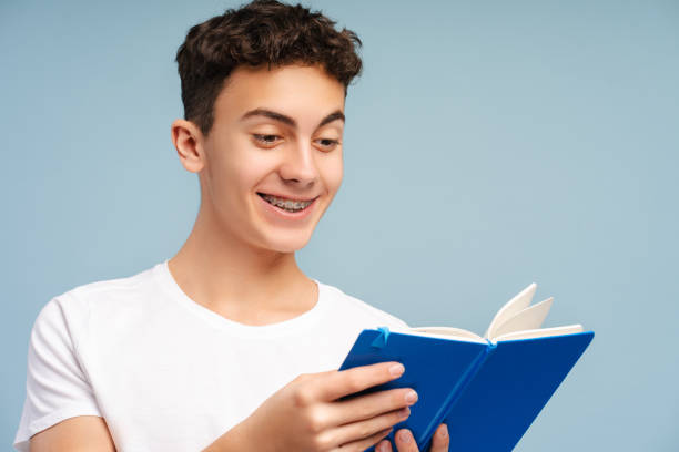 istock Smart smiling school boy wearing eyeglasses holding book reading isolated 2049159344