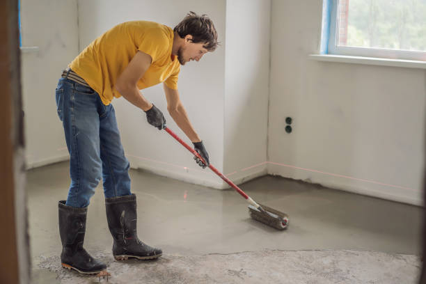 istock plasterer during floor covering works with self-levelling cement mortar, uses a needle roller 2049164661