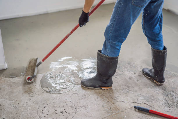 istock plasterer during floor covering works with self-levelling cement mortar, uses a needle roller 2049164663
