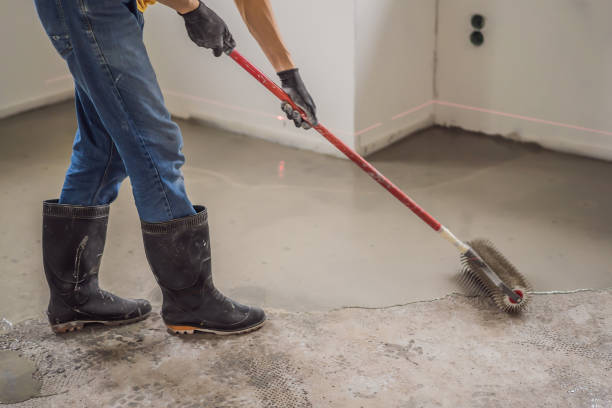 istock plasterer during floor covering works with self-levelling cement mortar, uses a needle roller 2049164664