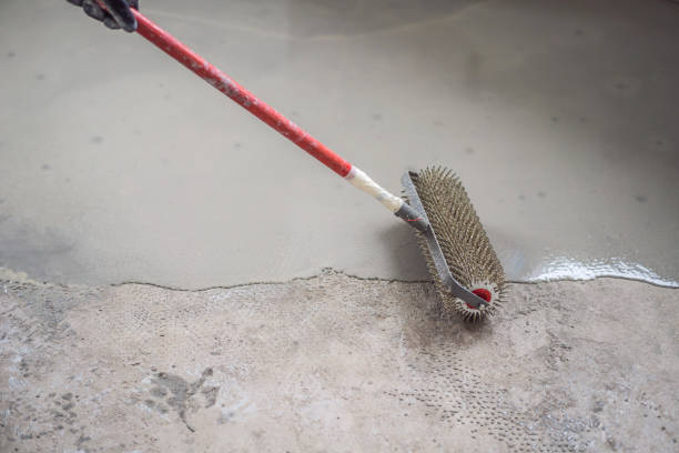 istock plasterer during floor covering works with self-levelling cement mortar, uses a needle roller 2049164959