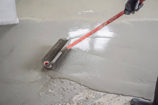 istock plasterer during floor covering works with self-levelling cement mortar, uses a needle roller 2049165184