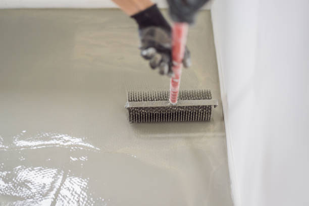 istock plasterer during floor covering works with self-levelling cement mortar, uses a needle roller 2049165188