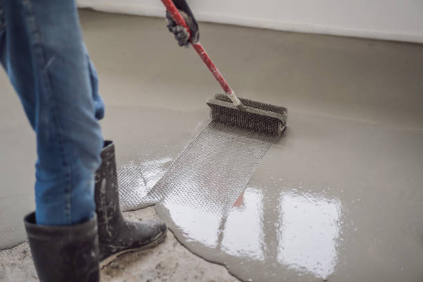 istock plasterer during floor covering works with self-levelling cement mortar, uses a needle roller 2049165192