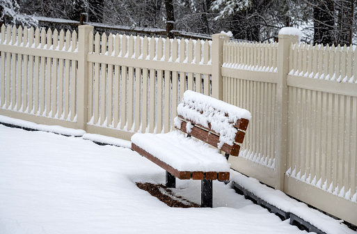 A garden gate decorated with a Christmas wreath all covered in snow.