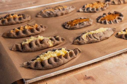 Karelian pasties with mashed potato and carrot filling just after backing, close-up photo with selective soft focus