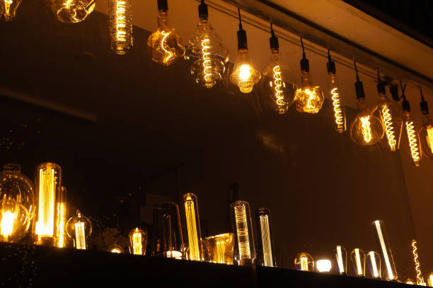 Row of different electric retro hanging lamp bulbs. Dark background. Warm yellow light