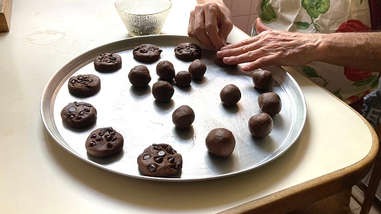Third age man in the kitchen preparing chocolate chips cookies at home