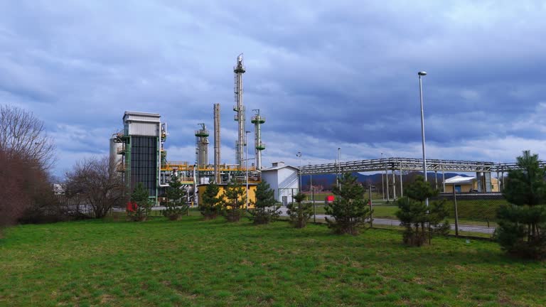 AERIAL Drone Shot of Industrial Factory with Tall Smoke Stacks Under Cloudy Sky