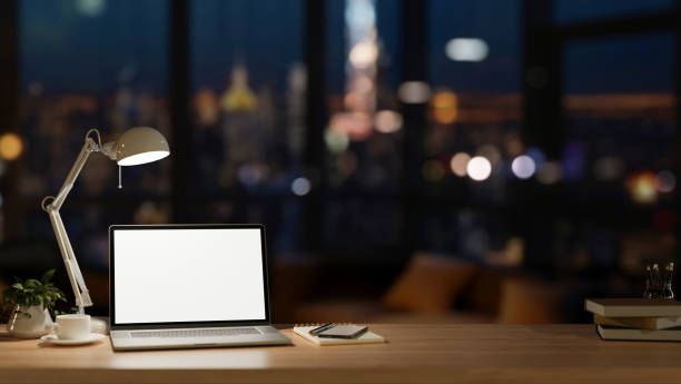 istock Office at night, a laptop computer mockup, a table lamp, and accessories on a wooden desk. 2049376320