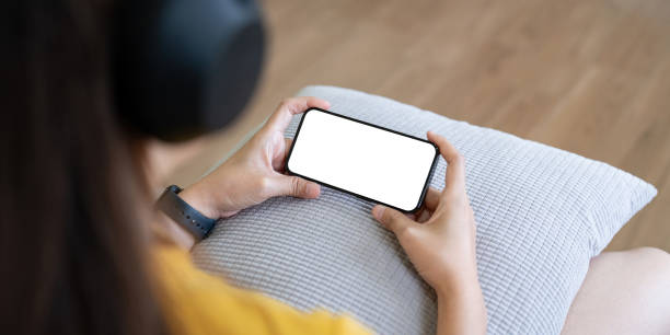 istock Mockup smartphone of a woman holding mobile phone with blank white screen while sitting listen to music at home 2049390111