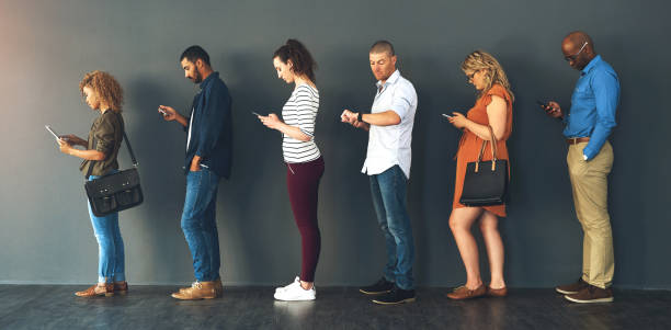 istock Businesspeople, interview and waiting in queue with technology or job recruitment, onboarding or internet. Men, women and meeting diversity in line or cellphone in office, human resources or hiring 2049406946